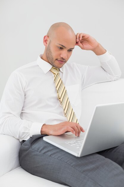 Hombre de negocios usando la computadora portátil en el sofá en casa