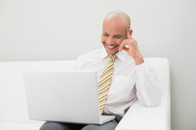 Hombre de negocios usando la computadora portátil en el sofá en casa