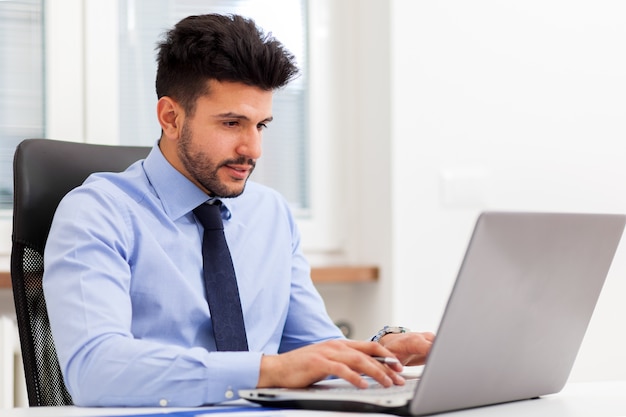 Hombre de negocios usando una computadora portátil en su oficina