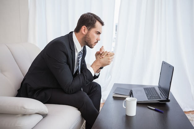 Hombre de negocios usando la computadora portátil en su sofá