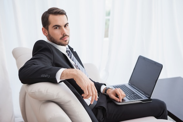 Hombre de negocios usando la computadora portátil en su sofá