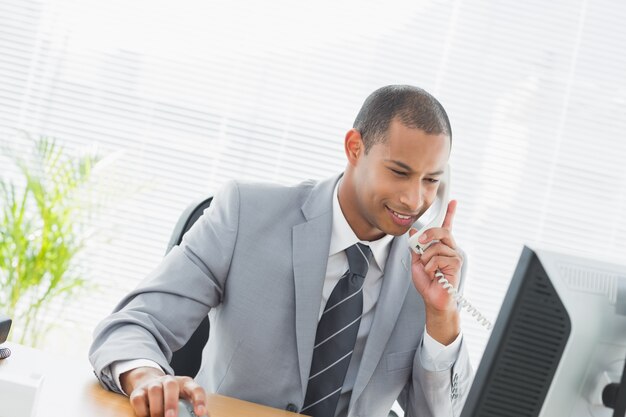 Hombre de negocios usando la computadora y el teléfono en la oficina