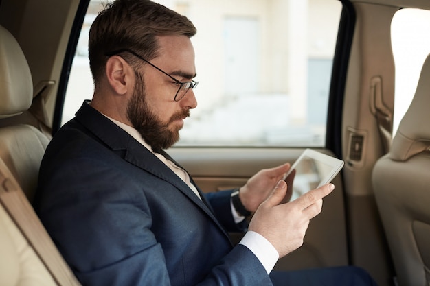 Hombre de negocios usando la pc de la tableta en el coche