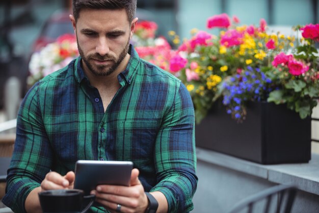 Hombre de negocios usando tableta digital mientras toma un café