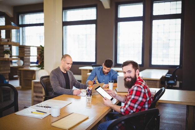 Foto hombre de negocios usando tableta mientras colegas que trabajan en la oficina