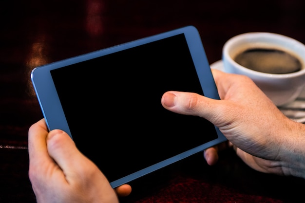 Hombre de negocios usando tableta tomando un café en el mostrador en un bar