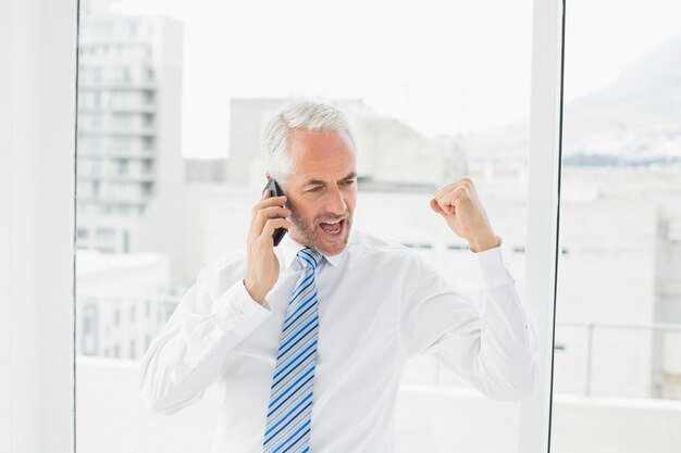 Hombre de negocios usando el teléfono móvil mientras aprieta el puño