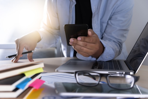 hombre de negocios usando teléfono teléfono inteligente y computadora portátil