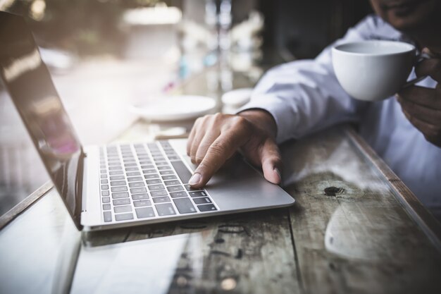 hombre de negocios, uso, teléfono inteligente y computadora portátil, en, wwoden, escritorio, negocio, ideas, concepto