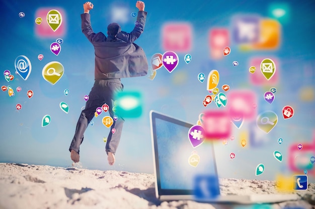 Foto hombre de negocios victorioso saltando dejando su computadora portátil con aplicaciones informáticas coloridas