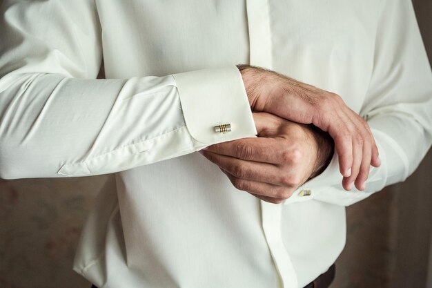 El hombre de negocios viste camisa blanca manos masculinas closeupgroom preparándose en la mañana antes de la ceremonia de la boda