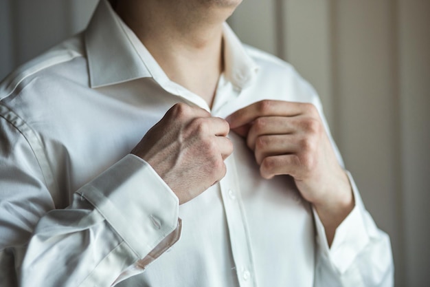 El hombre de negocios viste camisa blanca manos masculinas closeupgroom preparándose en la mañana antes de la ceremonia de la boda