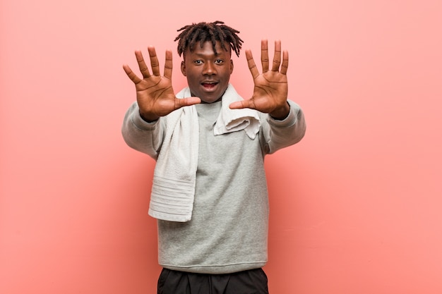 Hombre negro africano de la aptitud joven que muestra el número diez con las manos.