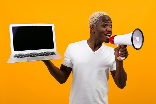 Hombre negro africano con cabello blanco habla en un megáfono sosteniendo una computadora portátil en amarillo