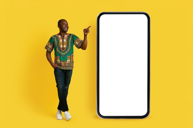 Hombre negro alegre apuntando a una gran maqueta de teléfono inteligente