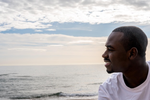 Hombre negro alegre en la playa durante la puesta de sol