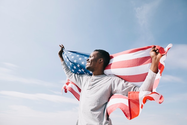 Foto hombre negro con bandera americana que simboliza la libertad.