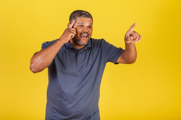 Hombre negro brasileño adulto señalando algo distante con el dedo sorprendido