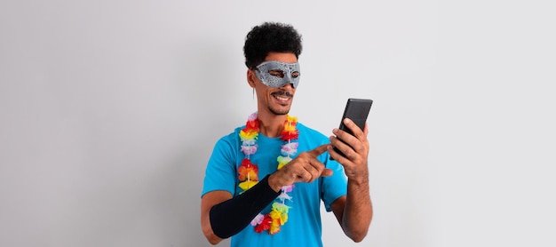 Hombre negro brasileño con traje de carnaval sosteniendo un móvil aislado en blanco