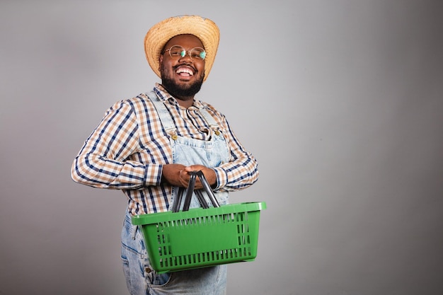 Hombre negro brasileño vestido con ropa de campo de festa junina festa de sao joao arraia con promociones de compras de canasta de mercado