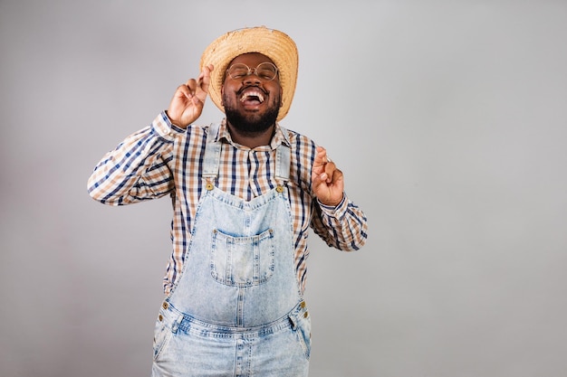 Hombre negro brasileño vestido con ropa de campo de festa junina festa de sao joao arraia signo de suerte dedos cruzados anhelo esperando