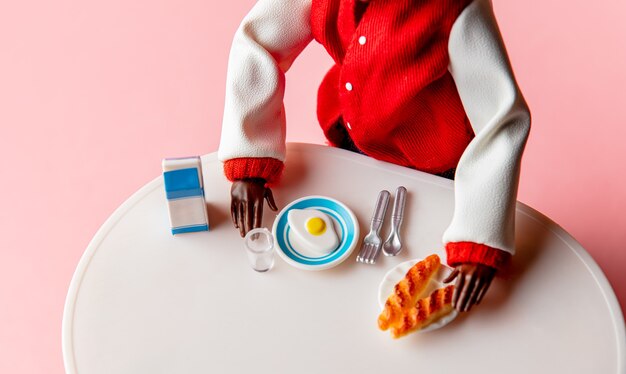 Hombre negro desayuna con huevos, leche y bollos en una mesa.