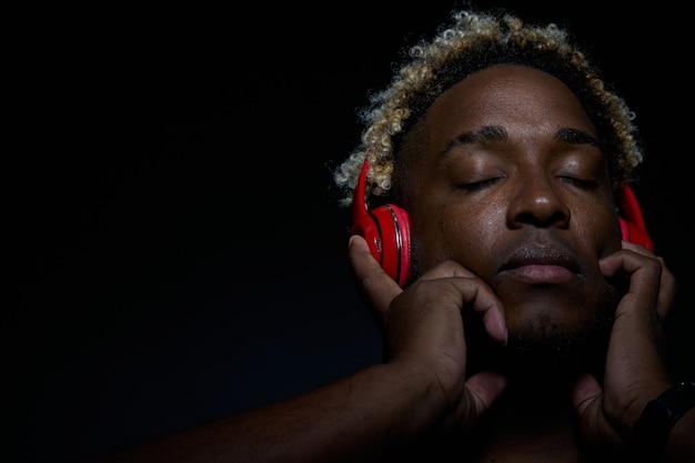 Hombre negro disfruta de la música en auriculares rojos