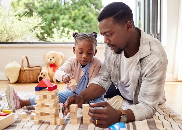 Hombre negro educación y bloques de construcción con la niña aprendiendo del padre en el piso de la sala de estar crecimiento del niño y juguetes para el desarrollo del niño con el padre enseñando a la hija en el salón de casa para jugar