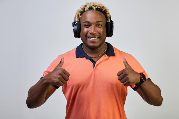 El hombre negro escucha música con auriculares da un pulgar hacia arriba con aprobación