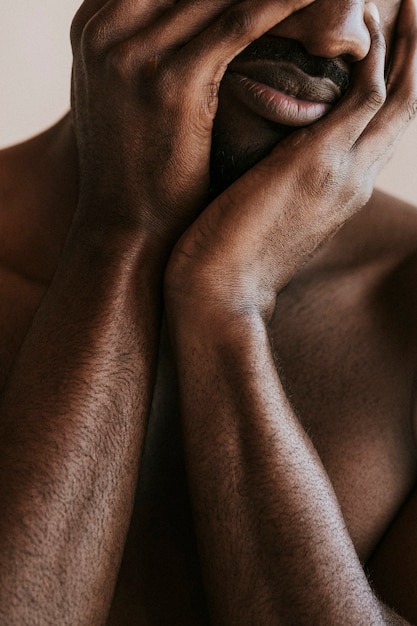 Hombre negro estresado cubriendo su rostro con las manos