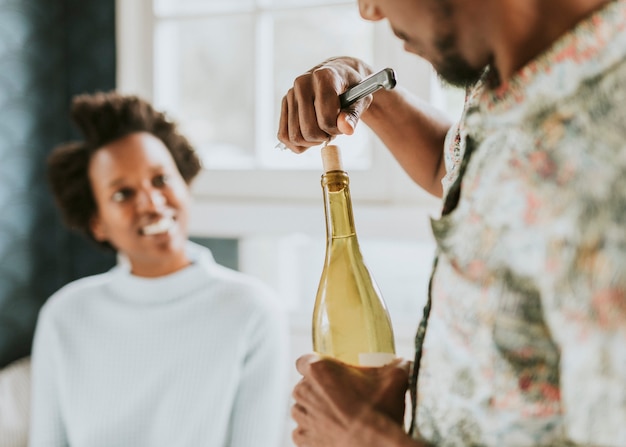 Hombre negro feliz descorchando una botella de vino