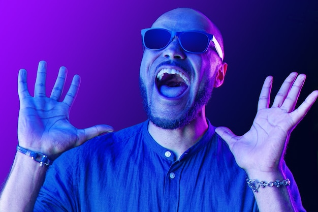 Hombre negro con gafas gritando de felicidad en luz de neón