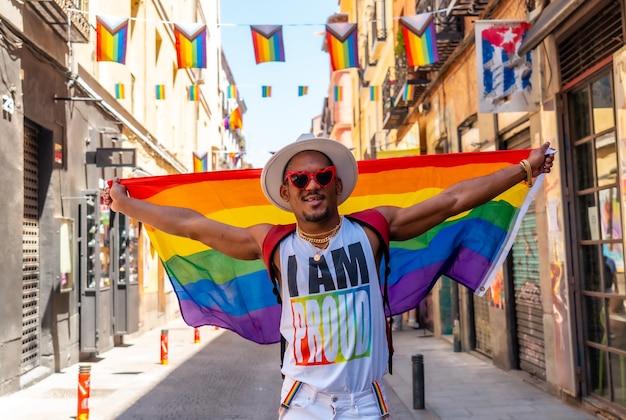 Un hombre negro gay disfrutando y sonriendo en la fiesta del orgullo con una bandera LGBT