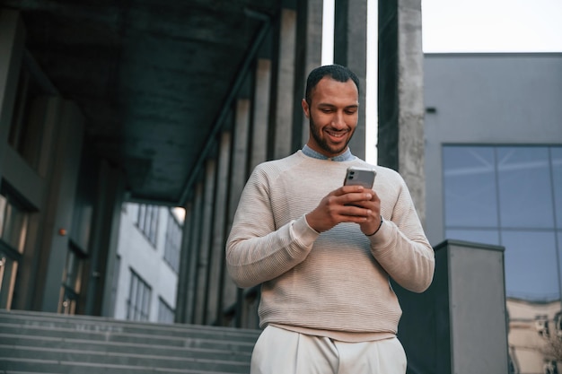 Hombre negro guapo está al aire libre cerca del edificio de negocios