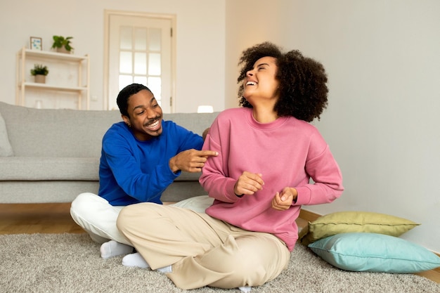 Hombre negro haciendo cosquillas a una mujer divirtiéndose y riéndose en casa