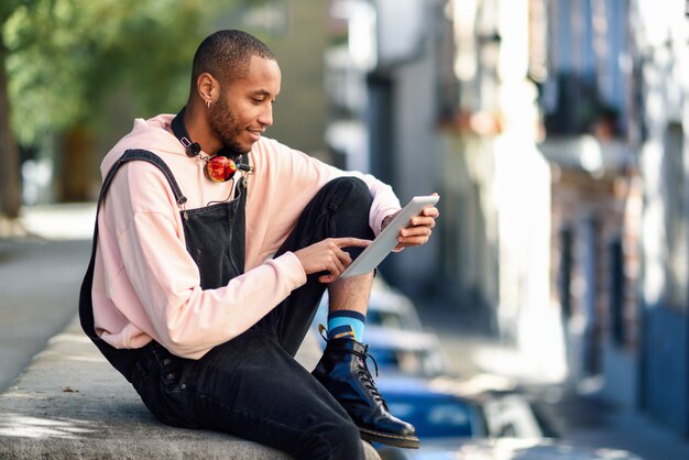 Hombre negro joven que usa la tableta digital en la ciudad