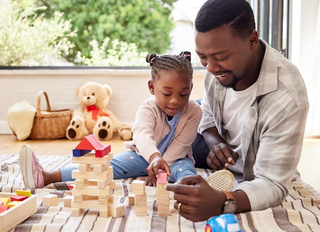 Hombre negro jugando y construyendo bloques con la niña aprendiendo del padre en el piso de la sala de estar Crecimiento del niño y juguetes para el desarrollo del niño con el padre enseñando a la hija en el salón de la casa para la educación