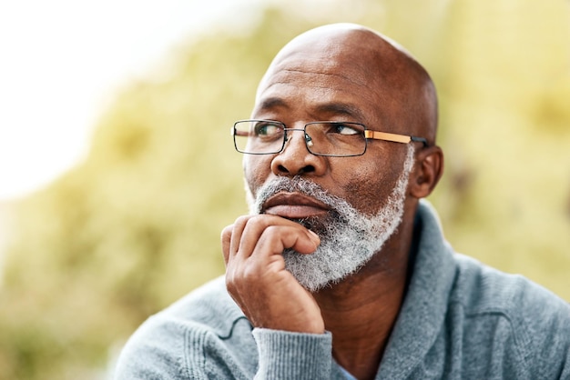 Hombre negro mayor y cara pensando al aire libre en la naturaleza para recordar la idea de la memoria o la visión Captura de cabeza de un anciano que piensa o planea un futuro seguro de vida o jubilación en un parque en verano