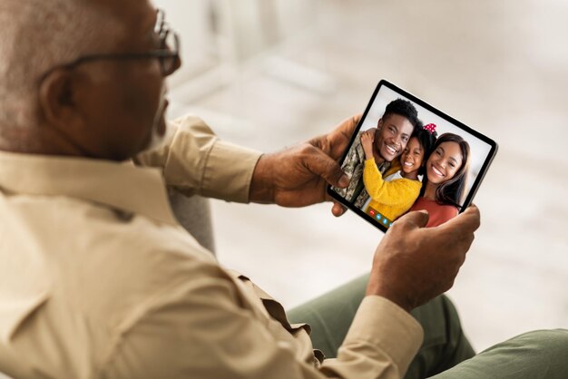 Hombre negro mayor llamando a su familia usando una tableta digital