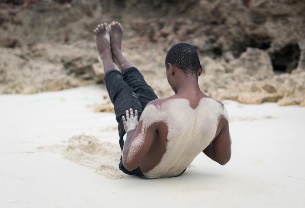 Hombre negro musculoso con entrenamiento en playa tropical