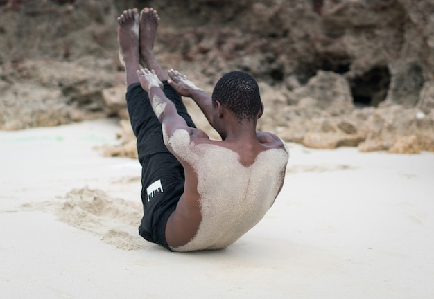 Hombre negro musculoso con entrenamiento en playa tropical