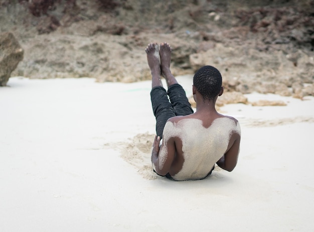 Hombre negro musculoso haciendo ejercicio en la playa tropical