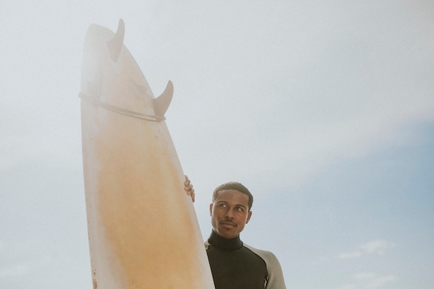 Hombre negro de pie junto a la tabla de surf