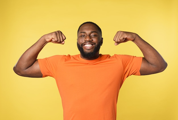 El hombre negro piensa que tiene músculos fuertes. pared amarilla