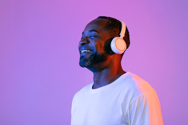 Hombre negro positivo escuchando música y sonriendo con auriculares