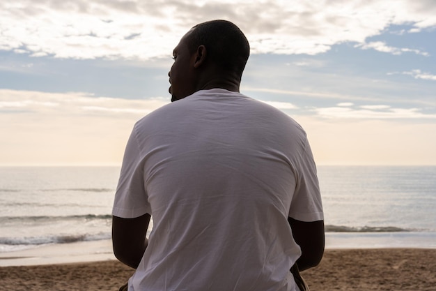 Hombre negro relajándose cerca del mar en la playa