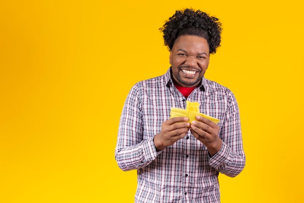 Hombre negro con ropa típica de festa junina comiendo deliciosa pamonha sobre fondo amarillo espacio libre para texto