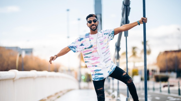 Hombre negro sonriente con gafas de sol disfrutando feliz en la calle