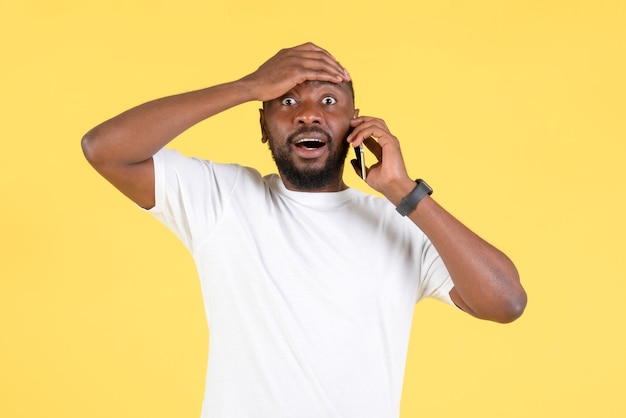 Hombre negro sorprendido hablando por teléfono con problemas de fondo amarillo