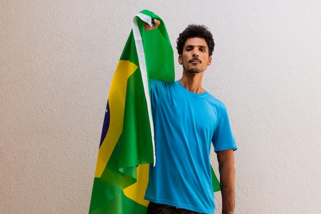 Hombre negro sosteniendo una bandera de Brasil aislada en blanco. Imagen de concepto de bandera y día de la independencia.